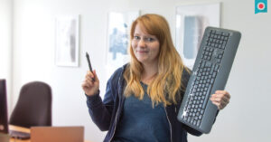 Digital Designerin mit Tastatur und Stift in der Hand