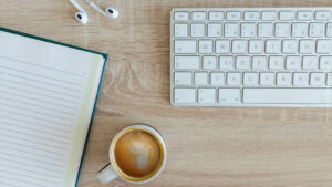 Schreibtisch mit Kaffee Tastaur und Notizbuch