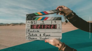 Filmklappe wird vor die Kamera gehalten, im Hintergrund ist eine Wüstenlandschaft
