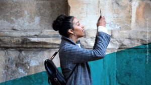 Junge Frau hält ihr Handy nach oben und schaut interessiert darauf