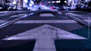Nächtliche Straße in der Stadt mit einem Pfeil, der auf den Horizont zeigt
