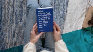 Person von oben auf einer Decke sitzend mit einem Buch in den Händen