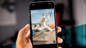 Smartphone, auf dem ein Mensch im Hasenkostüm in die Luft springt