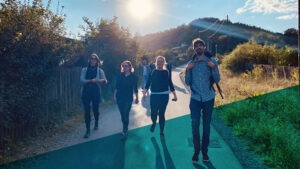 Eine Gruppe von Personen läuft im Sonnenschein einen Berg hinunter und lacht in die Kamera