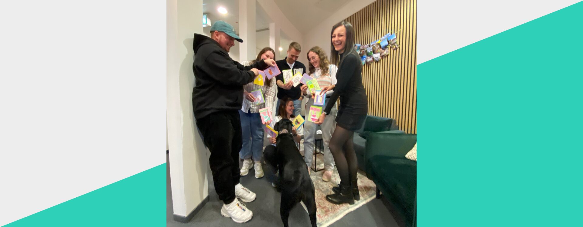 Mitarbeitende der Somengo halten Osterkarten so in den Händen, dass ein Herz gebildet wird und Bürohund Koda möchte auch dabei sein
