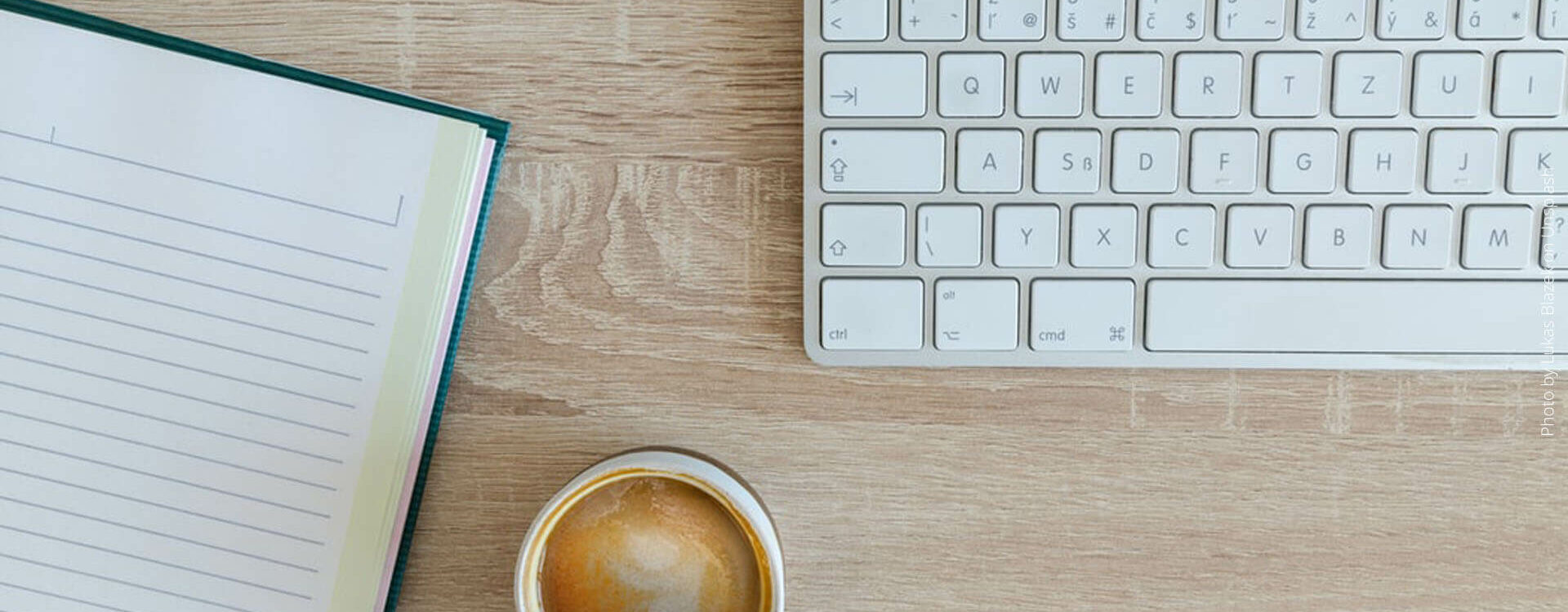 Schreibtisch mit Kaffee Tastaur und Notizbuch