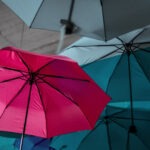 Pinker Regenschirm im Vordergrund, graue Regenschirme im Hintergrund