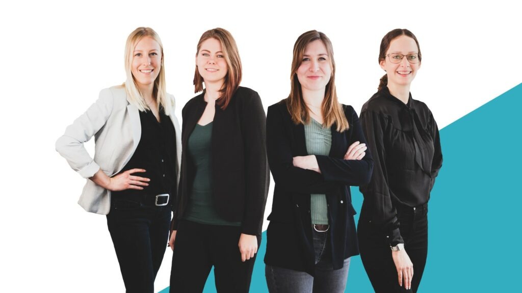 Vier Frauen in Business-Kleidung vor einem weiß-blauen Hintergrund