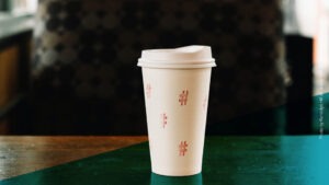Weißer Kaffee To-Go-Becher mit aufgemalten Hashtags