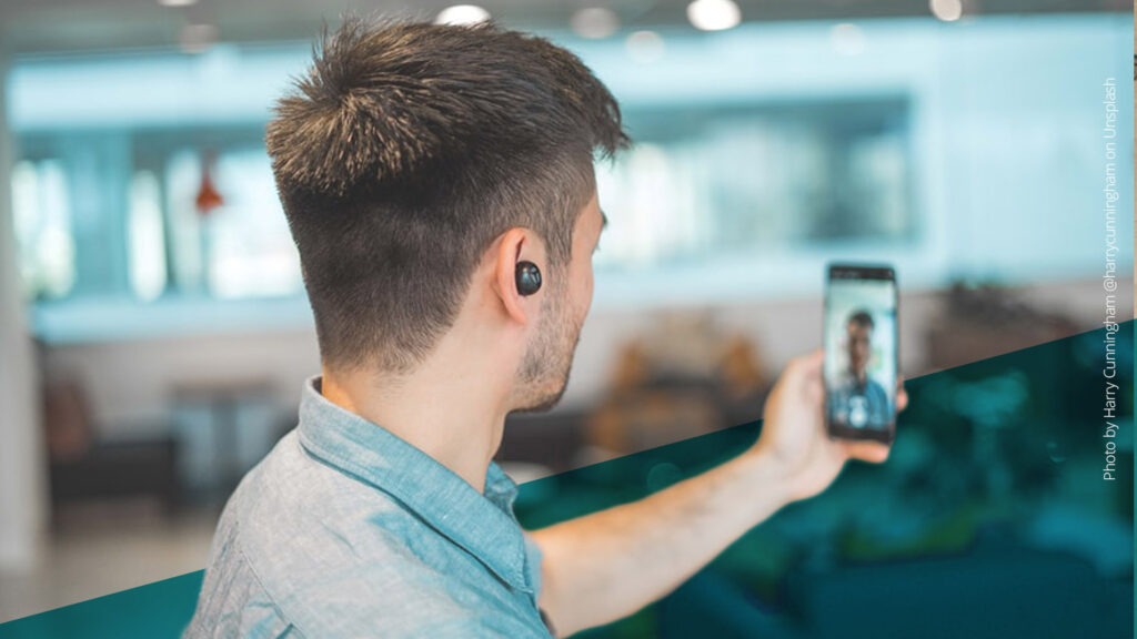 Mann mit Kopfhörern im Ohr macht ein Selfie mit seinem Smartphone