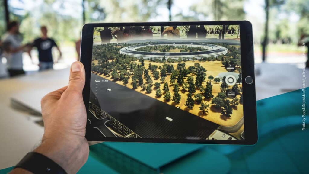 Hand hält ein Tablet, auf dem mit Augmented Reality eine Landschaft abgebildet ist