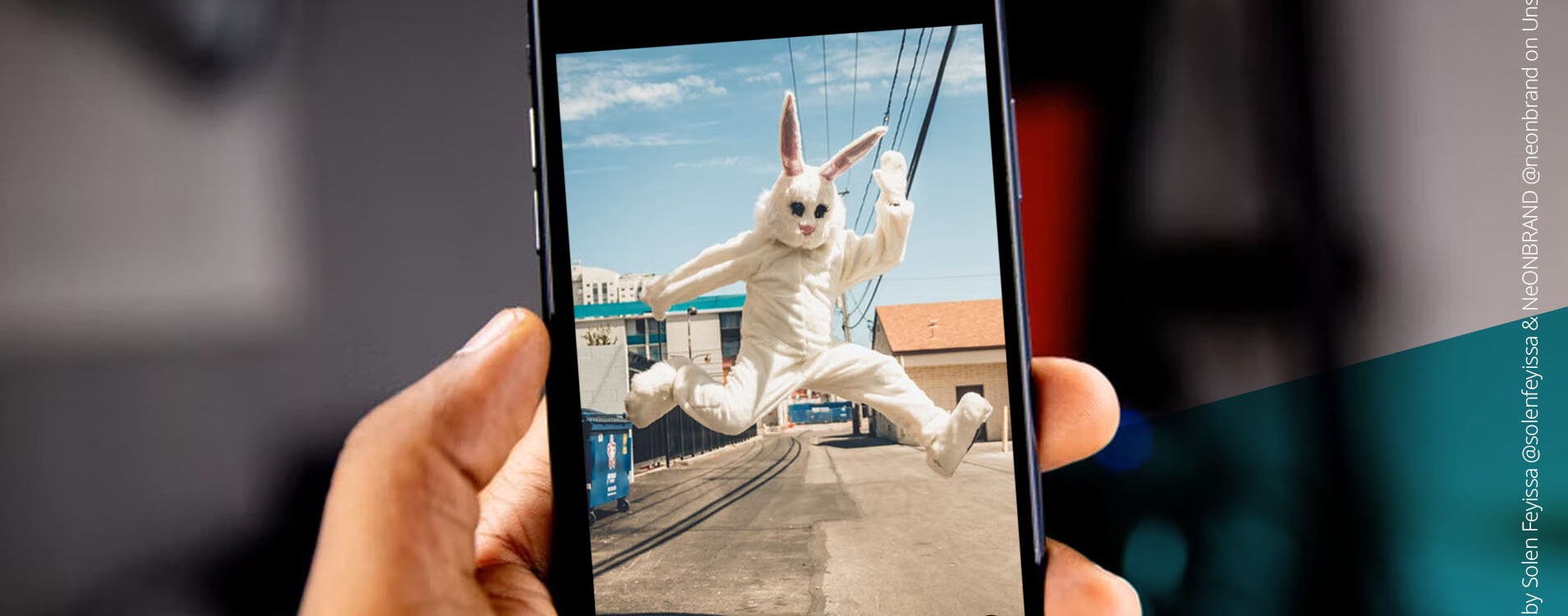 Smartphone, auf dem ein Mensch im Hasenkostüm in die Luft springt