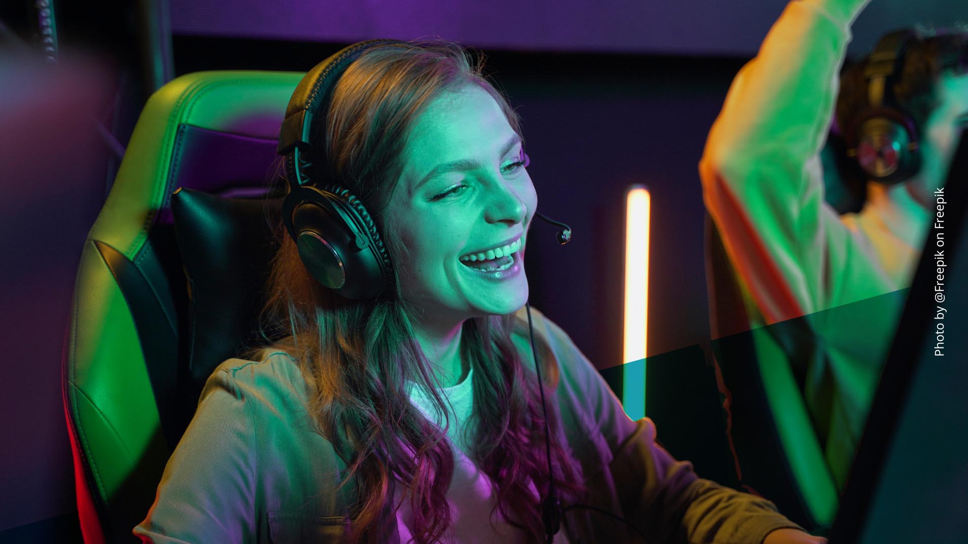Junge Frau spielt ein Videospiel, trägt Kopfhörer und lacht